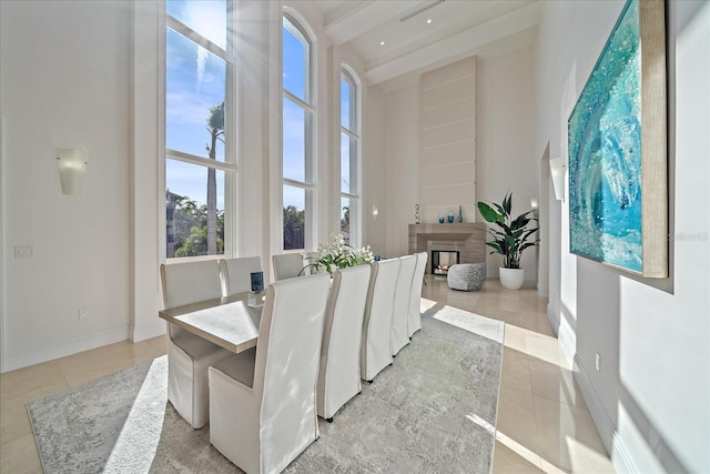 tiled dining area featuring a high ceiling and beam ceiling