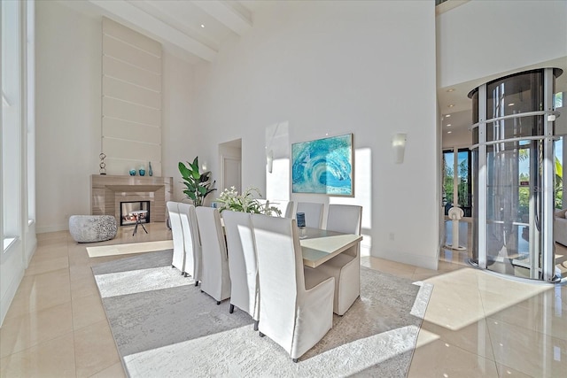 tiled dining space featuring beam ceiling, a multi sided fireplace, and a towering ceiling