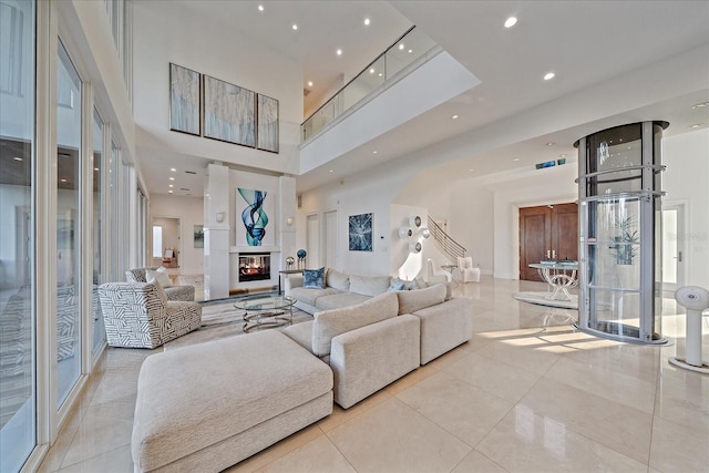 living room with a multi sided fireplace, a towering ceiling, and light tile patterned floors