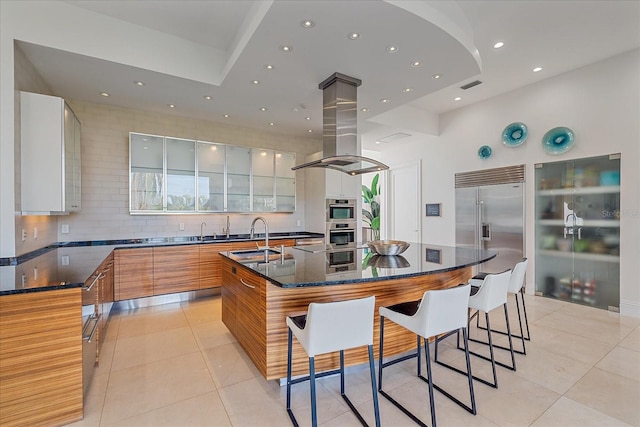 kitchen featuring stainless steel appliances, light tile patterned floors, a large island, white cabinets, and sink