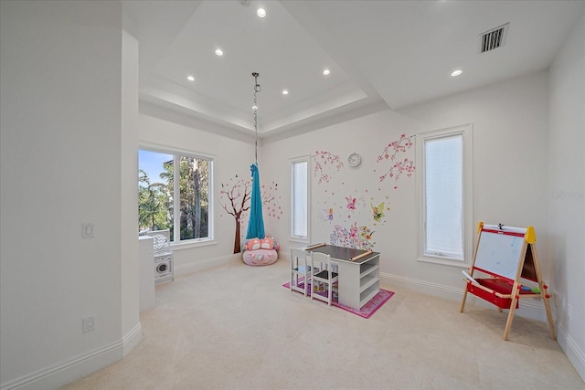 game room featuring light colored carpet and a tray ceiling