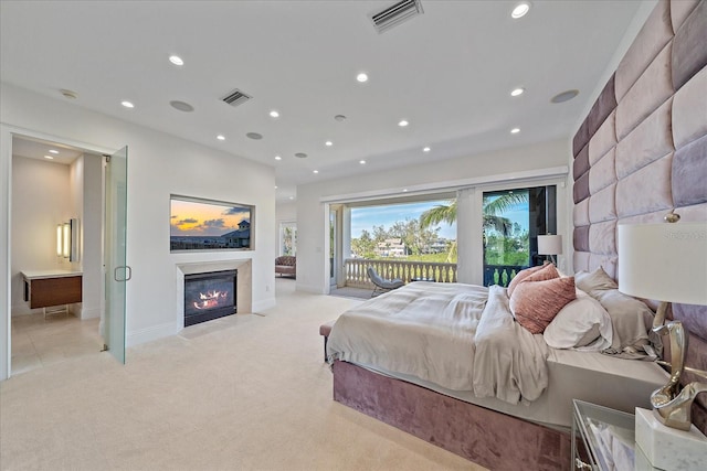 bedroom featuring ensuite bath, light colored carpet, and access to exterior