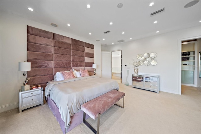 bedroom with light colored carpet and a spacious closet