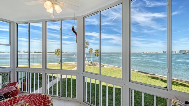 sunroom with a beach view, a water view, and ceiling fan