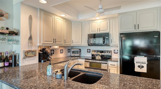 kitchen with ceiling fan, sink, dark stone counters, a tray ceiling, and black appliances