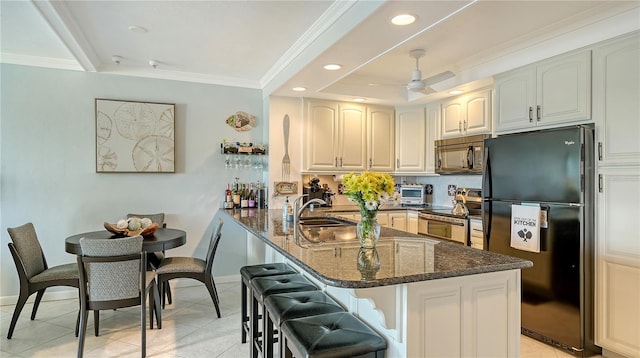 kitchen featuring ceiling fan, kitchen peninsula, dark stone countertops, a breakfast bar, and black appliances