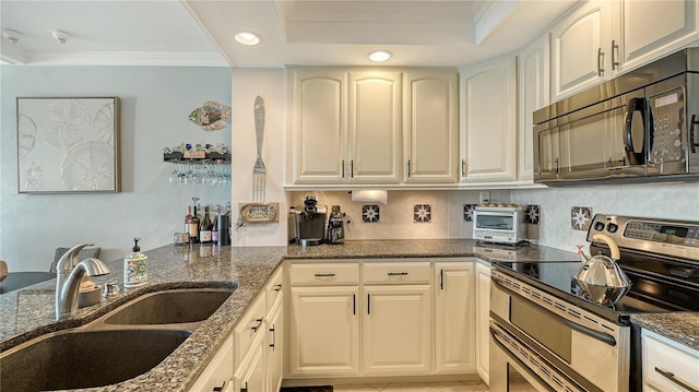 kitchen featuring stainless steel range with electric stovetop, dark stone counters, white cabinets, sink, and ornamental molding