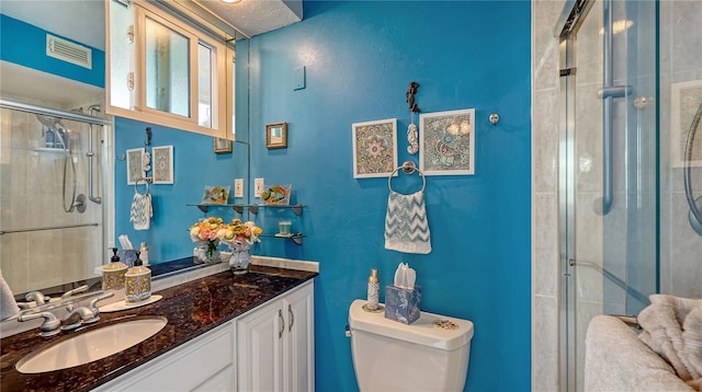 bathroom with a shower with door, vanity, and toilet