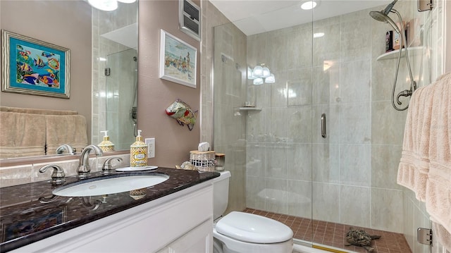 bathroom featuring vanity, toilet, and a shower with shower door