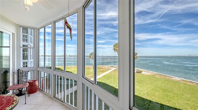 sunroom / solarium featuring ceiling fan, a water view, and a beach view