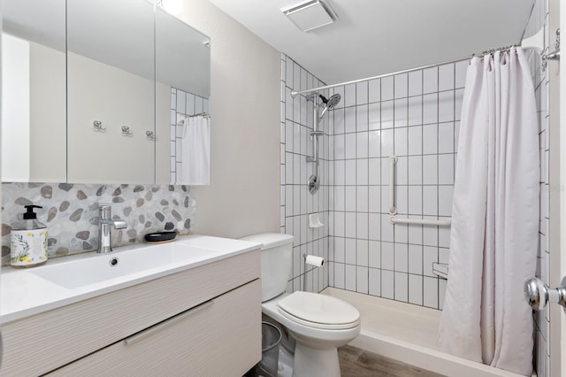 bathroom featuring tasteful backsplash, walk in shower, vanity, wood-type flooring, and toilet