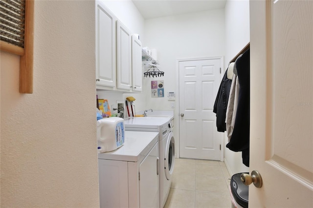 washroom with cabinets, light tile patterned flooring, sink, and washing machine and clothes dryer