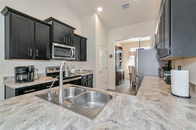 kitchen with appliances with stainless steel finishes, light hardwood / wood-style floors, and sink