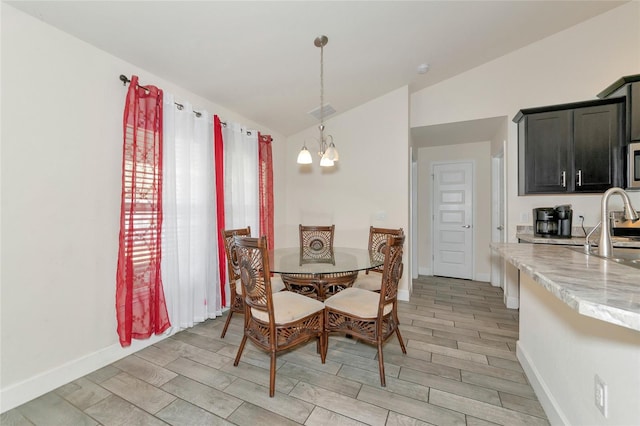 dining room featuring vaulted ceiling, sink, and a notable chandelier