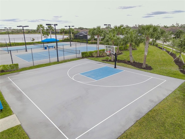 view of sport court featuring tennis court and a lawn