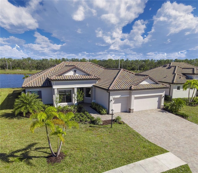 view of front of house featuring a front lawn, a garage, and a water view