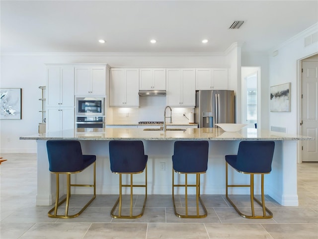 kitchen featuring a kitchen breakfast bar, appliances with stainless steel finishes, white cabinets, and a large island