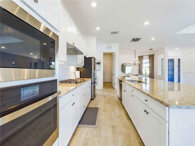 kitchen featuring a large island with sink, sink, white cabinetry, and a notable chandelier