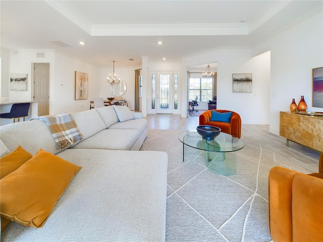 living room featuring light wood-type flooring, a chandelier, crown molding, and a tray ceiling