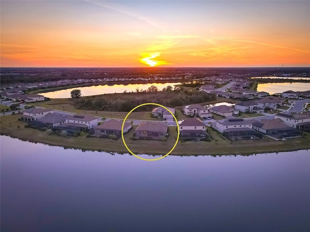 aerial view at dusk featuring a water view