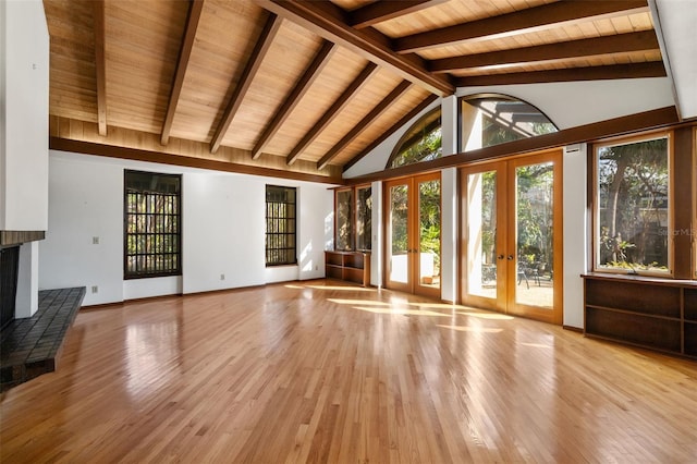 unfurnished living room featuring beamed ceiling, light hardwood / wood-style floors, wood ceiling, and french doors