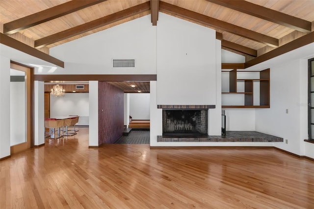 unfurnished living room featuring beamed ceiling, wood ceiling, and a brick fireplace