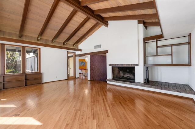 unfurnished living room featuring beam ceiling, wooden ceiling, high vaulted ceiling, a fireplace, and light wood-type flooring