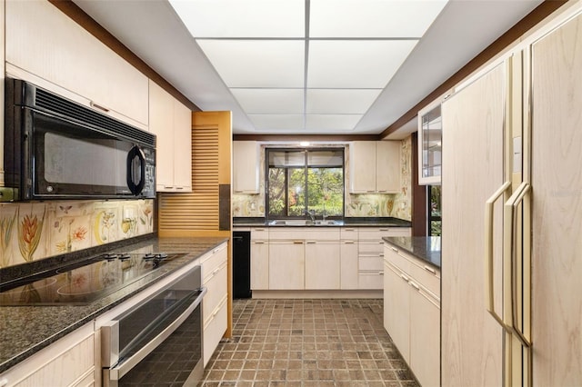 kitchen with cream cabinets, sink, dark stone counters, and black appliances