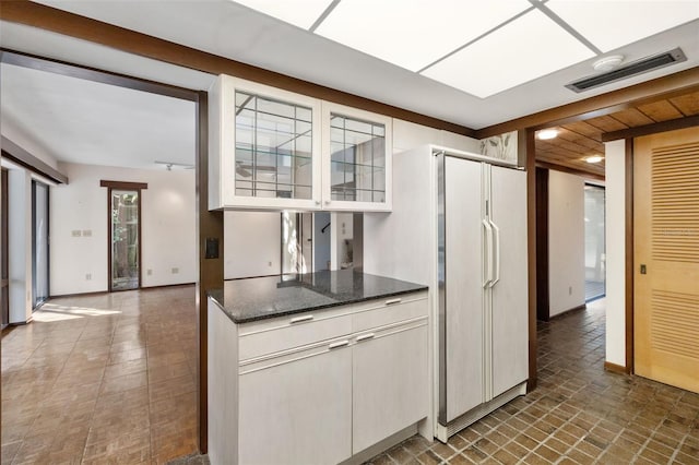 kitchen with white cabinets, white fridge, and dark stone counters