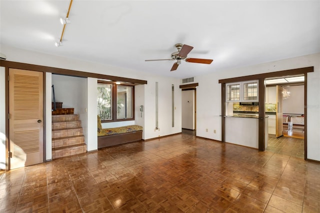 unfurnished living room with ceiling fan with notable chandelier