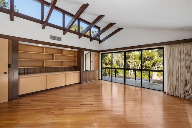 unfurnished living room with light hardwood / wood-style flooring, high vaulted ceiling, and a skylight