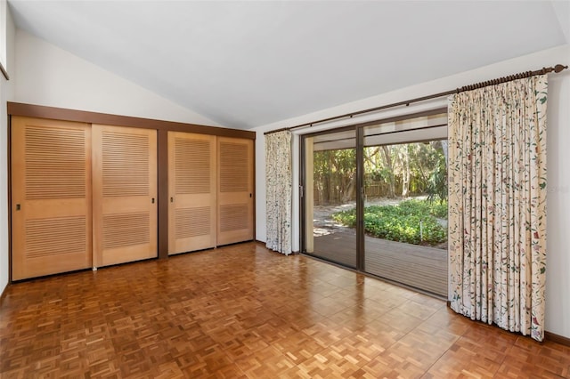 unfurnished bedroom with access to exterior, multiple closets, lofted ceiling, and parquet flooring