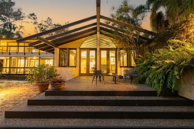 back house at dusk with a balcony and a patio area