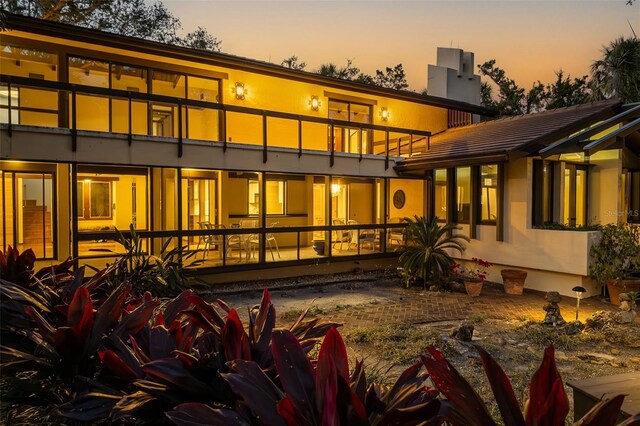 back house at dusk with a balcony