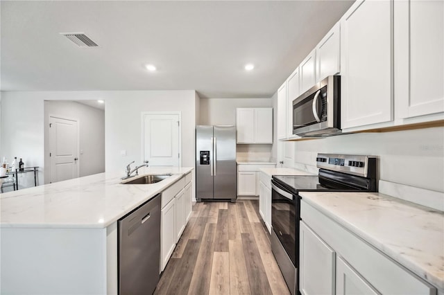 kitchen featuring appliances with stainless steel finishes, sink, white cabinets, a kitchen island with sink, and light hardwood / wood-style floors