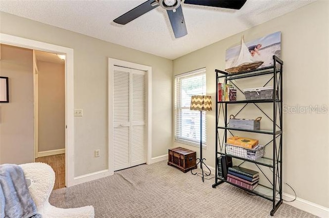 interior space with ceiling fan, carpet floors, and a textured ceiling