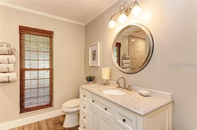 bathroom with wood-type flooring, vanity, toilet, and ornamental molding