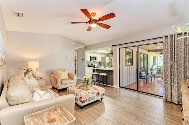 living room with ceiling fan, lofted ceiling, and light wood-type flooring