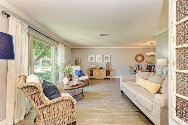 living room featuring ornamental molding, a notable chandelier, and light wood-type flooring