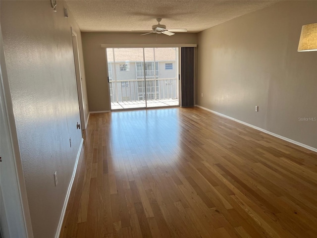 empty room with a textured ceiling, wood-type flooring, and ceiling fan