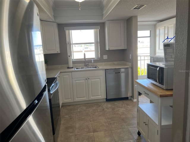 kitchen with sink, white cabinetry, crown molding, a textured ceiling, and stainless steel appliances