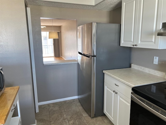 kitchen featuring stainless steel fridge, butcher block counters, white cabinetry, electric range, and decorative light fixtures