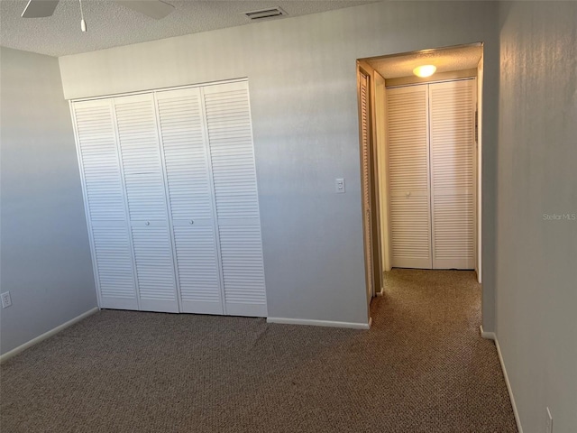 unfurnished bedroom with dark carpet, a closet, and a textured ceiling