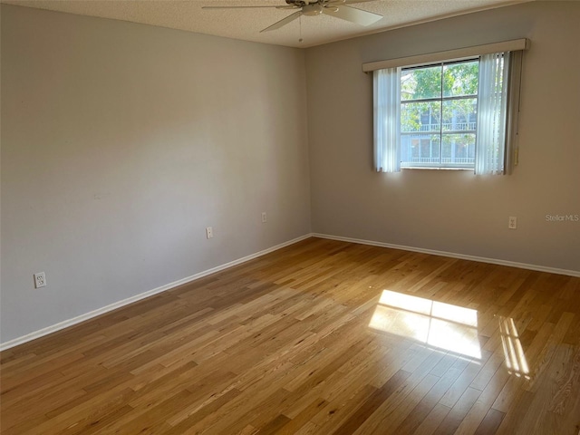 empty room featuring ceiling fan, light hardwood / wood-style flooring, and a textured ceiling