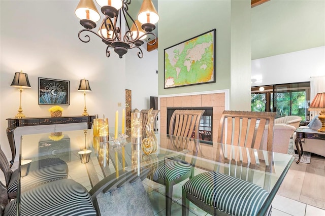 tiled dining space featuring a notable chandelier, a towering ceiling, and a tile fireplace