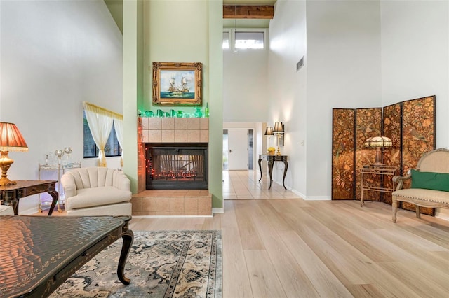 interior space featuring hardwood / wood-style floors, a high ceiling, and a tiled fireplace