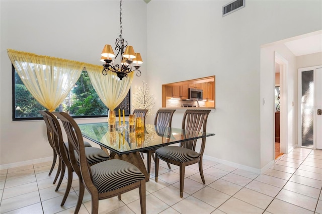 tiled dining room with a notable chandelier and a high ceiling