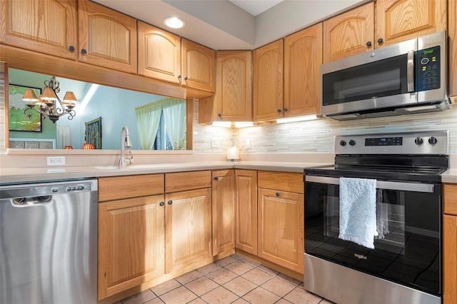 kitchen featuring backsplash, sink, light tile patterned floors, appliances with stainless steel finishes, and a chandelier