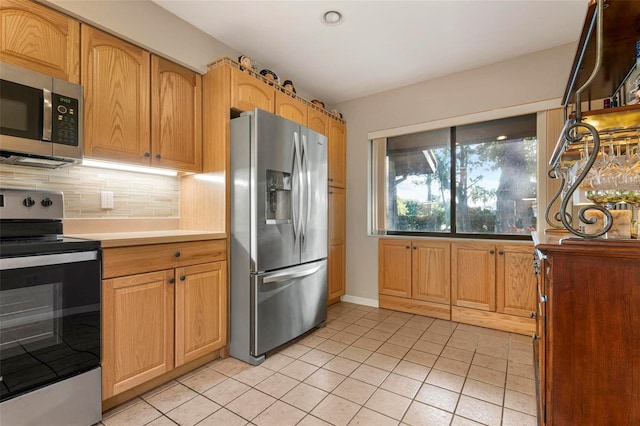 kitchen featuring tasteful backsplash, light tile patterned flooring, and appliances with stainless steel finishes