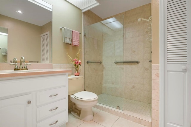 bathroom with tile patterned flooring, a tile shower, vanity, and toilet